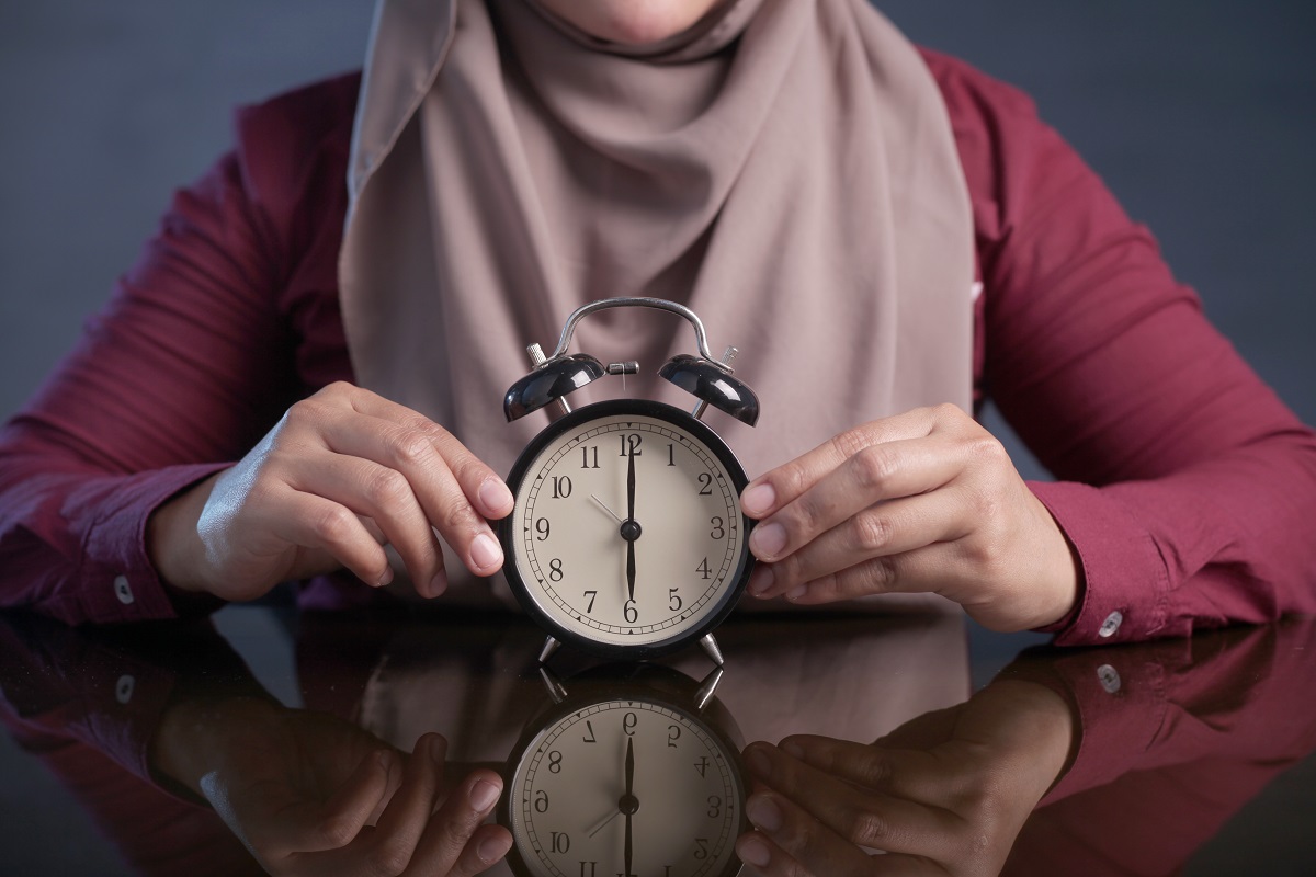 Muslim woman holding a clock.